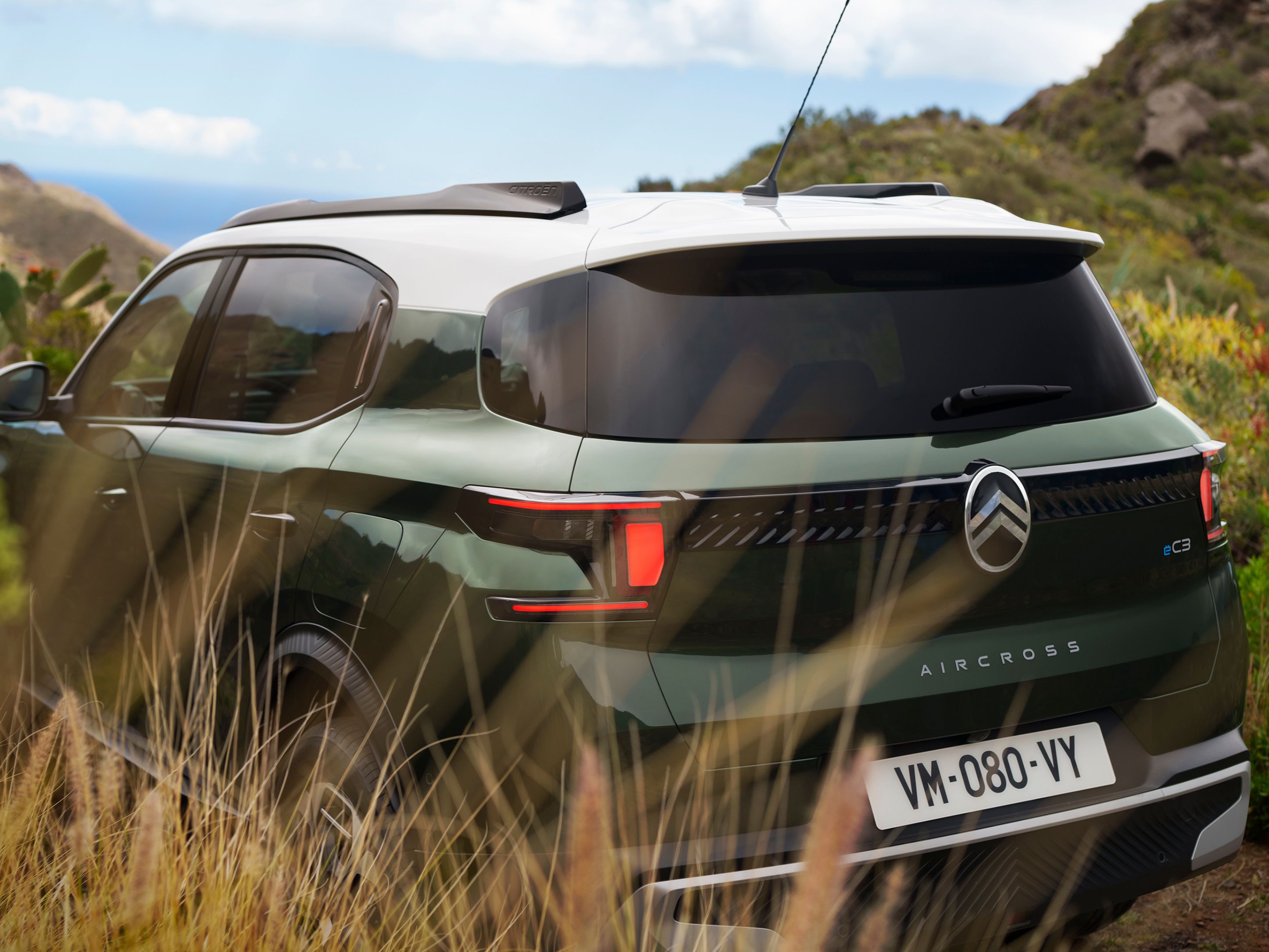 Dreiviertel-Heckansicht im Freien des Citroën ë-C3 Aircross SUV zeigt markantes Zweifarbdesign für sichere, vielseitige und erschwingliche Mobilität.