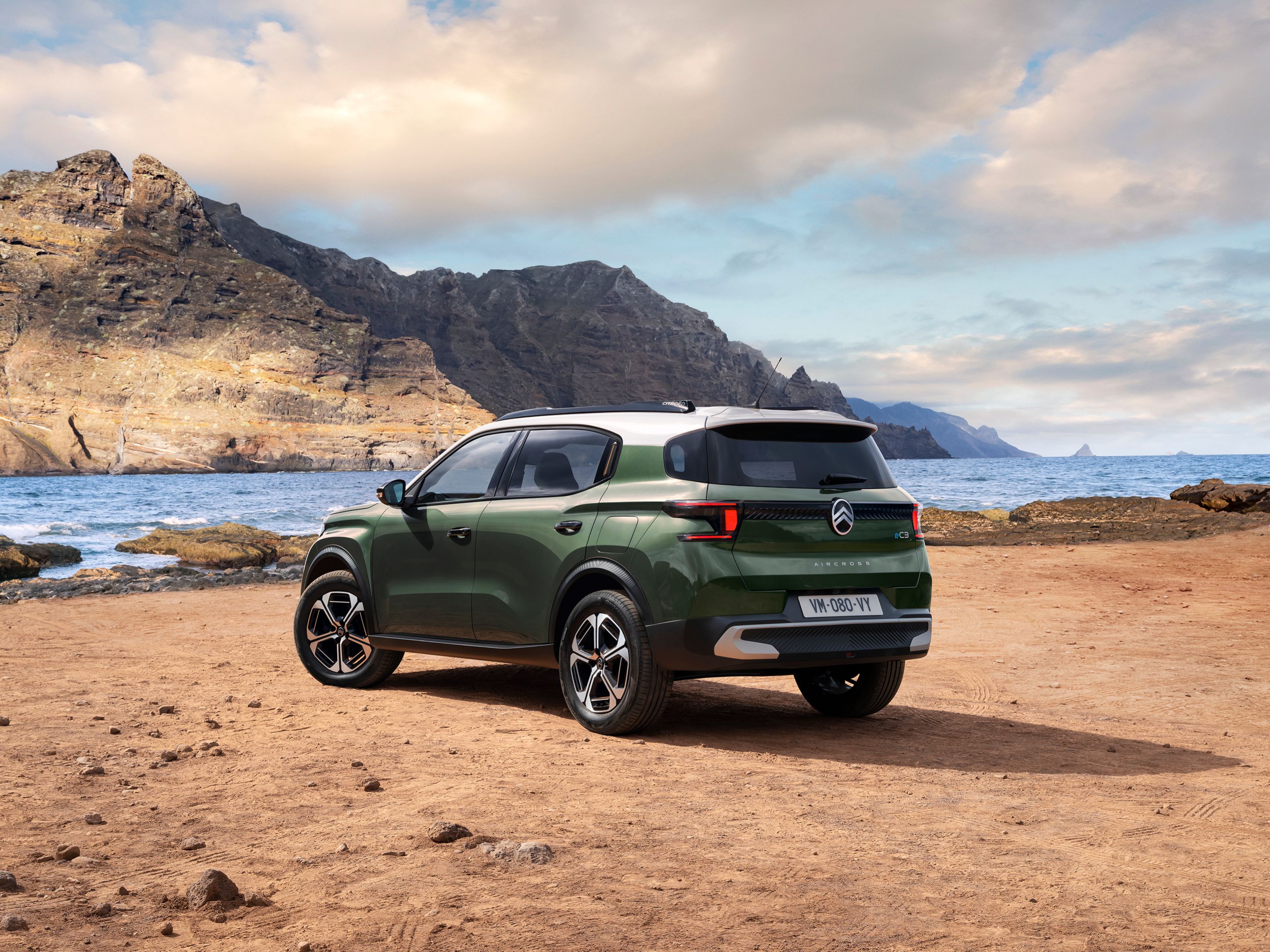 Dreiviertel-Heckansicht am Meer des Citroën ë-C3 Aircross SUV präsentiert modernes SUV-Design für vielseitige und erschwingliche Mobilität.